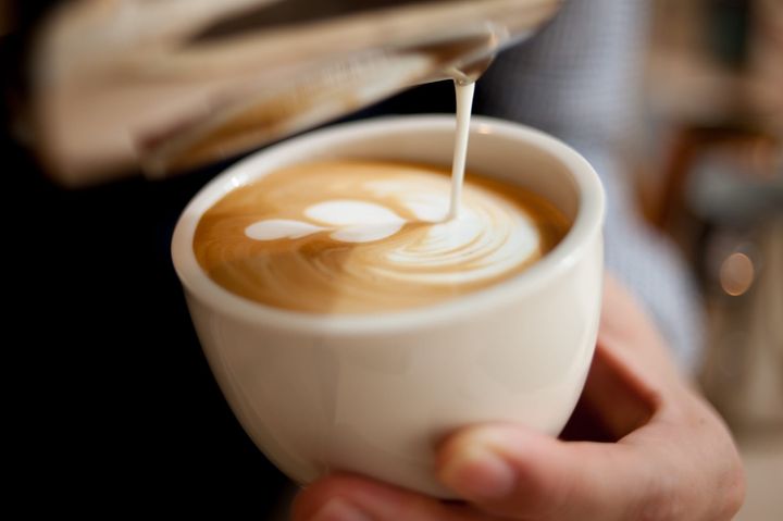 Steamed milk being poured into a cup of coffee to make latte art