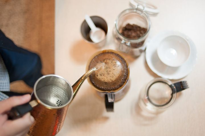 Hot water being poured over ground coffee in a pour-over dripper